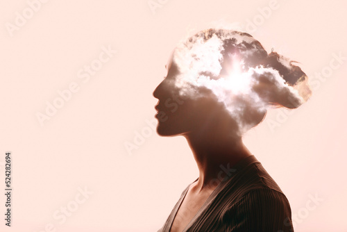 Atmosphere pressure and woman mental health contemplation concept. Multiple exposure clouds and sun on female head silhouette. photo