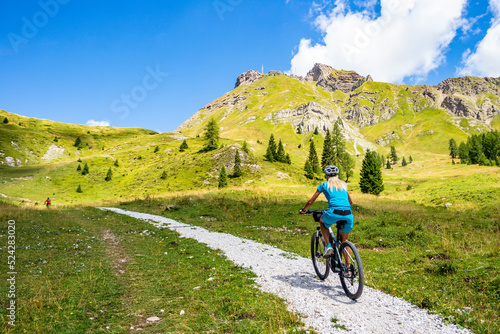 Background with woman cyclist on a path of the Pale di San Martino di Castrozza, Trentino Alto Adige - Italy