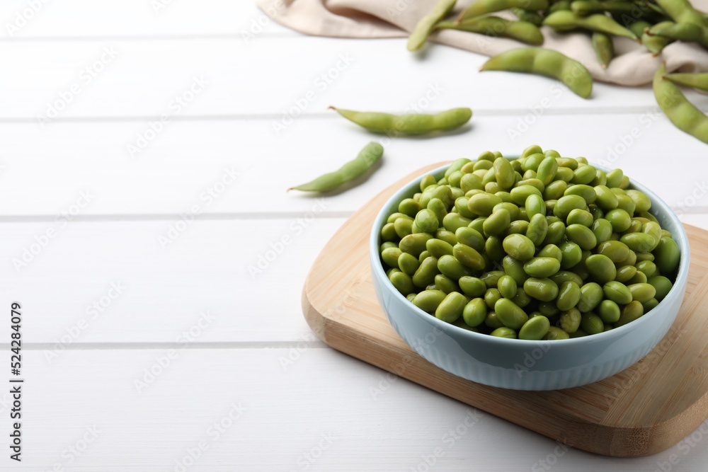 Bowl of delicious edamame beans on white wooden table, space for text Bowl of delicious edamame beans on white wooden table, space for text