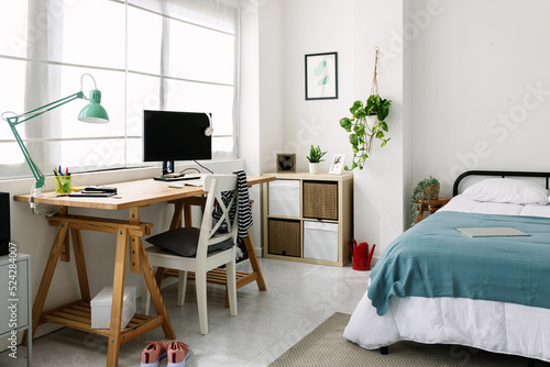 Cozy interior millennial teenage room with bed, laptop and desk photo