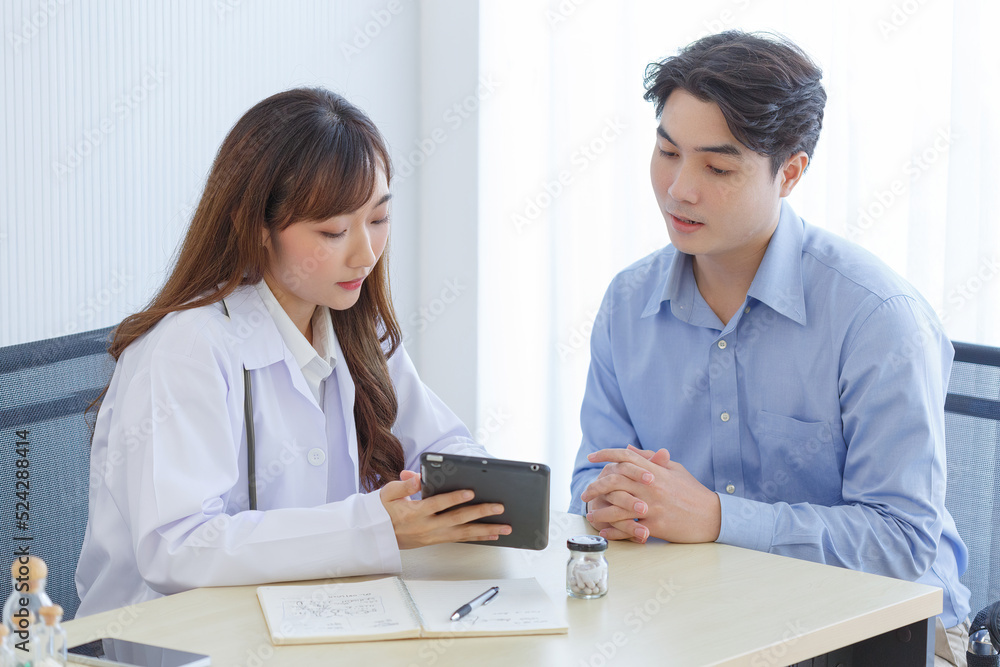 Female doctor and young male patient while consult and .explain. Doctor and patient sitting together at table in examination room. Female doctor and young male patient while consult and .explain. Doctor and patient sitting together at table in examination room.