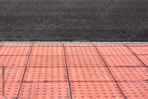 Tactile tiles for the blind. Panels for the blind laid on asphalt. Guide tape for the disabled. Red new tactile tiles for the visually impaired. Equipped modern pedestrian crossing with new asphalt.