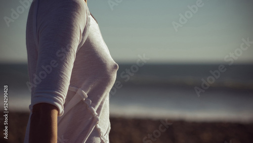 The upper part of the female body in a white T-shirt on the background of the sea  photo