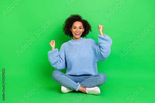 Full length portrait of delighted excited girl raise fists achieve triumph isolated on green color background