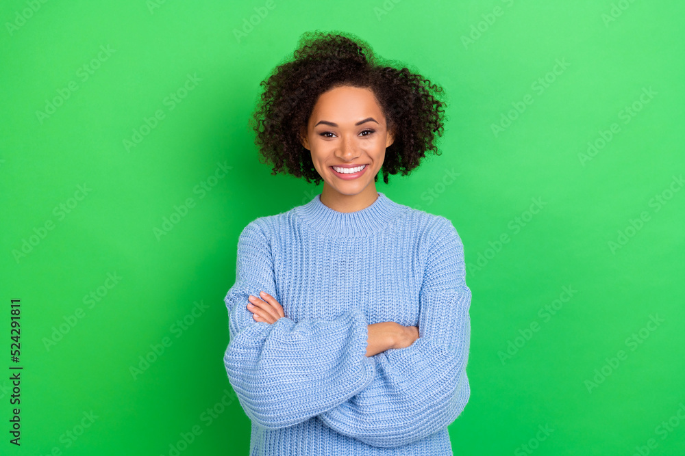 Obraz premium Photo of cheerful adorable lovely girl perming coiffure dressed blue oversize sweater hands crossed isolated on green color background