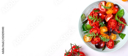 Web banner with salad with red  black and yellow cherry tomatoes  arugula and basil served on wheat straw plate. Mockup with copy space. Healthy eating