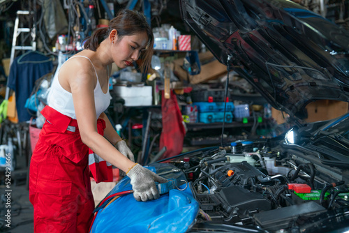 Asian mechanic woman or technician use tools to monitor pressure and gas of car engine and she also look to gauge to analysis and maintenance the car in garage.