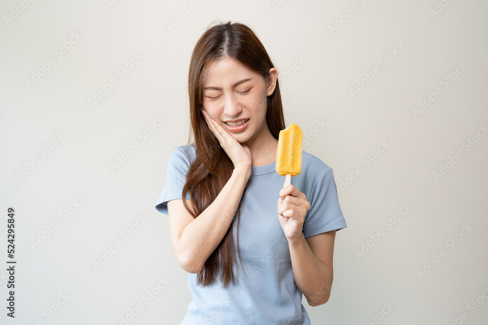 Face expression suffering from sensitive teeth, Asian young woman touching cheek Face expression suffering from sensitive teeth, Asian young woman touching cheek
