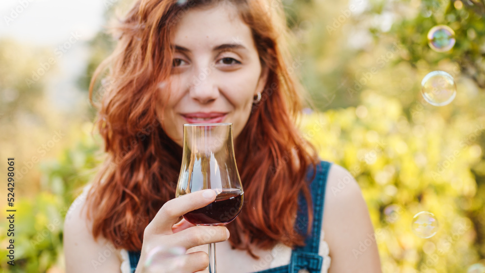 Fototapeta premium Woman with glass of red wine in the vineyard