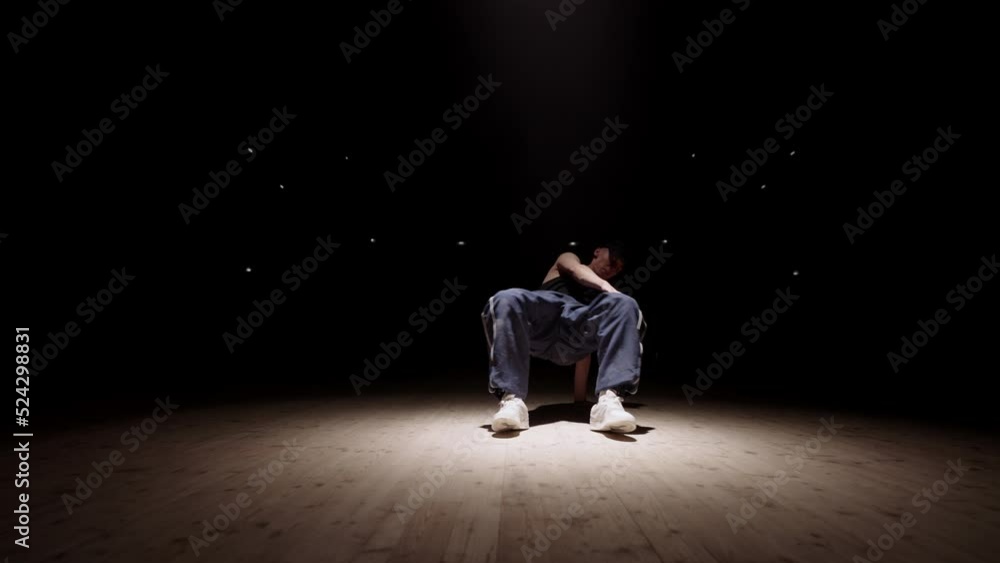b-boy is dancing breakdance in rehearsal room or on stage in soffit light, active and expressive man b-boy is dancing breakdance in rehearsal room or on stage in soffit light, active and expressive man