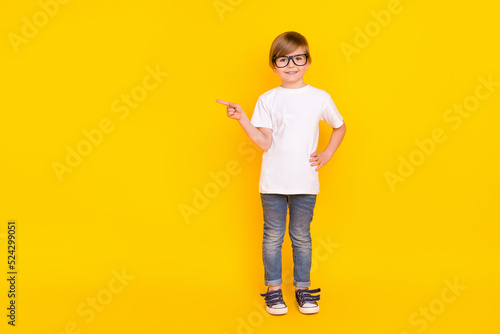Full length body size view of handsome cheery trendy pre-teen boy showing ad idea isolated over bright yellow color background