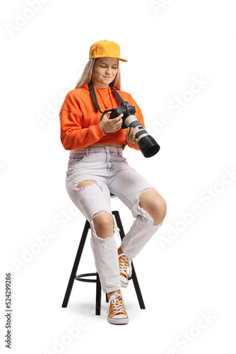 Young female sitting and looking at a display of a professional camera