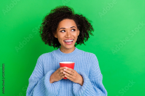 Photo of girlish pretty nice girl with curly hairstyle wear blue sweater holding cup of coffee isolated on green color background