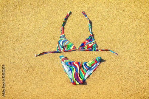Colorful swimsuit lying down on the golden sandy beach. Copy space. Top view.
