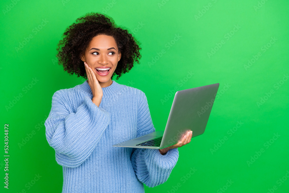 Photo of impressed young lady hold laptop look promo wear sweater isolated on green color background Photo of impressed young lady hold laptop look promo wear sweater isolated on green color background