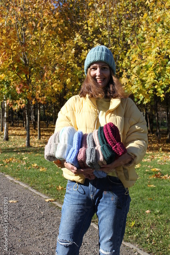 Hats crocheted knitted in the hands of a girlon the street. Product listing for sale. Urban style. Fashion. Autumn photo