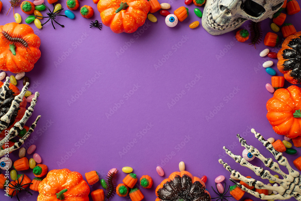 Fototapeta premium Halloween concept. Top view photo of pumpkins skull skeleton hands candies eyes spiders and centipedes on isolated violet background with copyspace in the middle