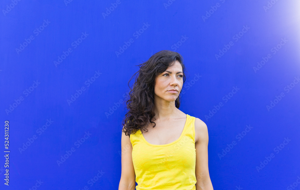 Woman standing near blue wall in park Woman standing near blue wall in park