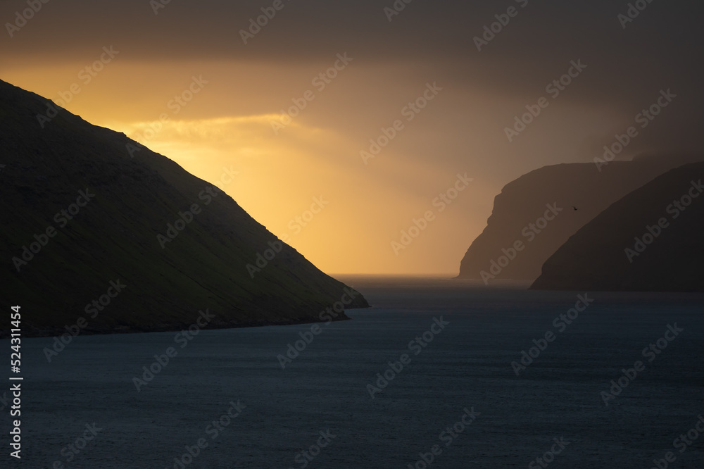 Sea water and cliffs against orange sunrise sky Sea water and cliffs against orange sunrise sky