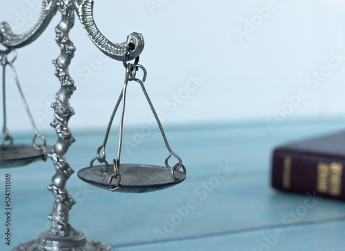 Photography A close-up of an ancient silver scale of justice and closed Holy Bible Book on a wooden table with white background