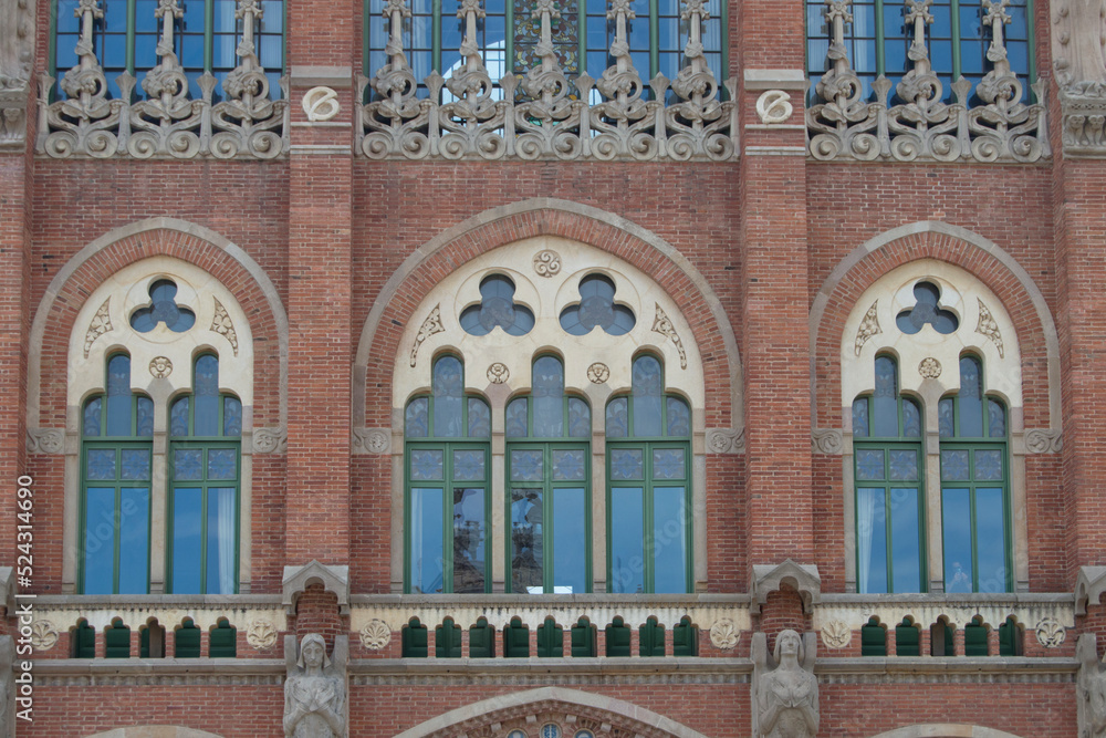 Three modernisme windows in a brick façade with stone decoration of one of the modernist pavilions of the  santa creu i San Pau  hospital in Barcelona. Spain