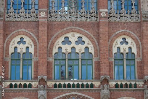 Three modernisme windows in a brick façade with stone decoration of one of the modernist pavilions of the  santa creu i San Pau  hospital in Barcelona. Spain photo