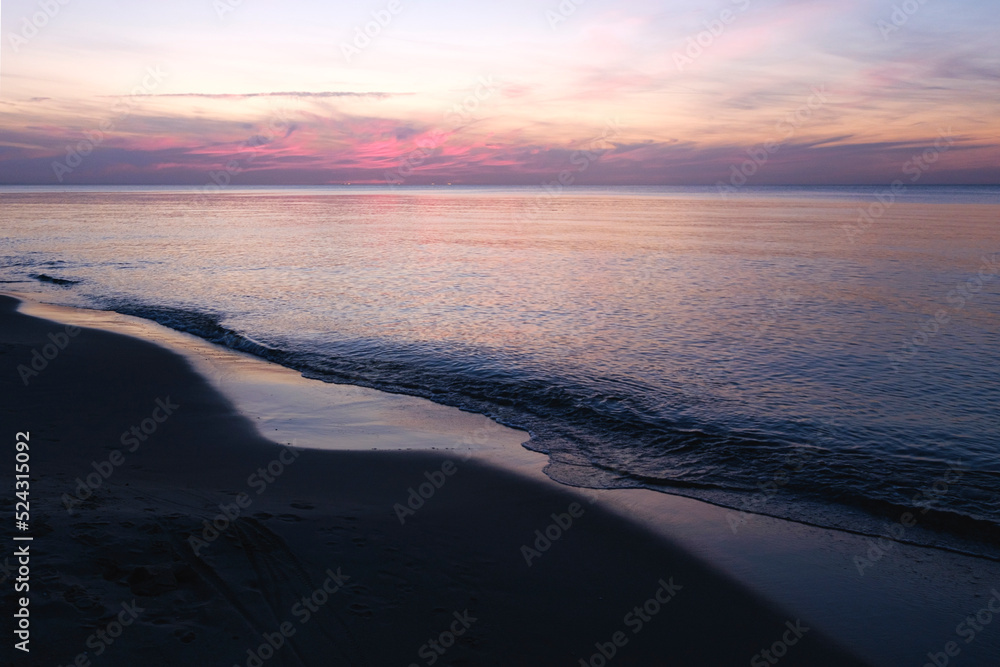 Baltic sea sunset sky, silver purple colors of sea calm water. Romantic beach landscape.