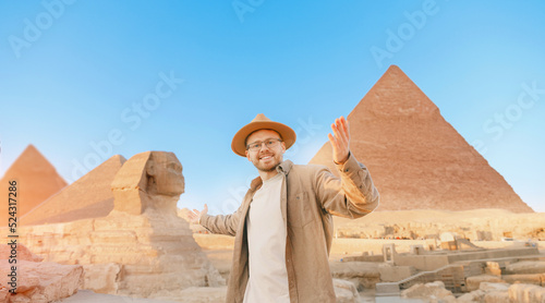 Travel man in hat background pyramid of Egyptian Giza and Sphinx, sunset Cairo, Egypt