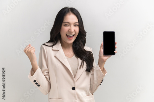 Slika na platnu Portrait photo of young beautiful Asian woman feeling happy or surprise shock and holding smart phone with black empty screen on white background can use for advertising or product presenting concept