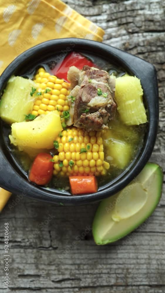 Typical Colombian Sancocho in a black ceramic bowl on a rustic wooden base. Vertical video. Typical Colombian Sancocho in a black ceramic bowl on a rustic wooden base. Vertical video.