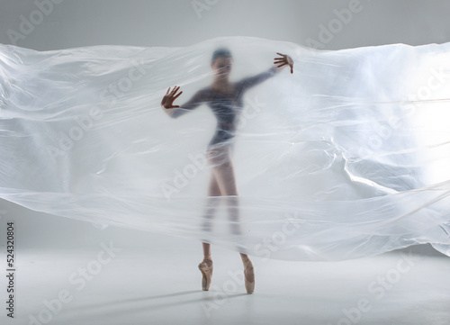 Ballerina in dark ballet leotard dancing on ballet pointe shoes in white studio 