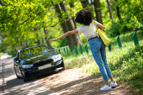 Curly-haired young girl hitchhiking and looking excited