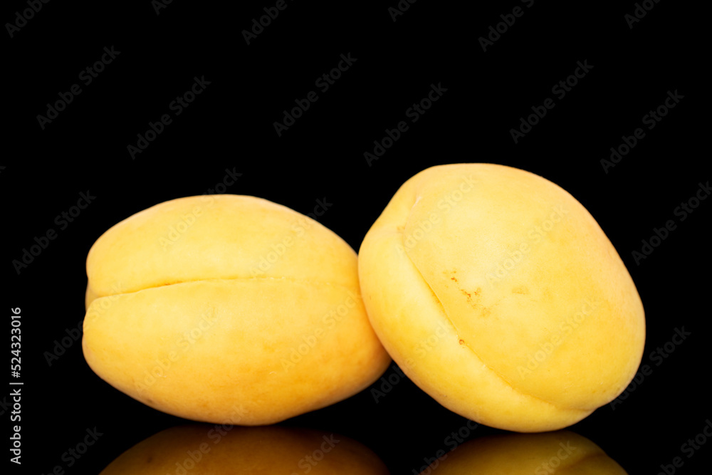 Several bright yellow juicy pineapple apricots, macro, isolated on a black background.
