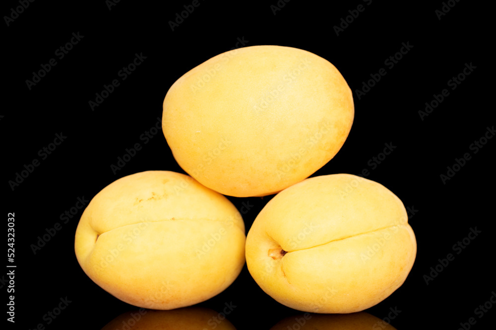 Three bright yellow juicy pineapple apricots, macro, isolated on a black background.
