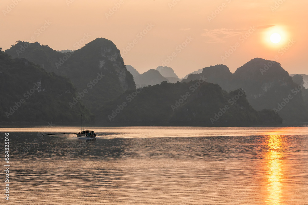 Sunset in Ha Long Bay with fishing boat on the left