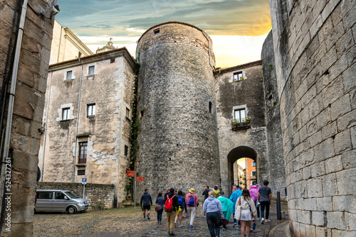 A tour group enters the historic walled old town in the Barri Vell medieval village of Girona Spain in the Catalonian district. photo
