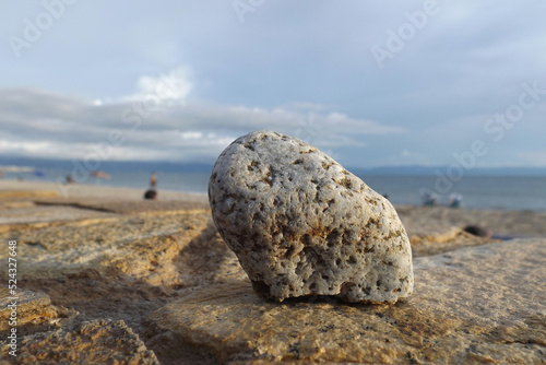 Roca pequeña sobre piso de piedra con un paisaje de playa,oceano,montañas,nubes y cielo de fondo,Small rock on rock floor with a landscape of beach,ocean, mountains, clouds and sky in the background

 photo