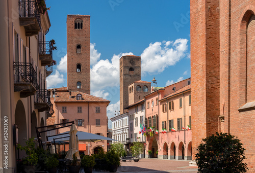 View of Duomo square with the town hall among old houses and medieval towers under beautiful sky in Alba, Langhe, Piedmont, Italy. photo