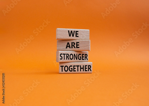 We are stronger together symbol. Wooden blocks with words We are stronger together. Beautiful orange background. We are stronger together concept. Copy space.