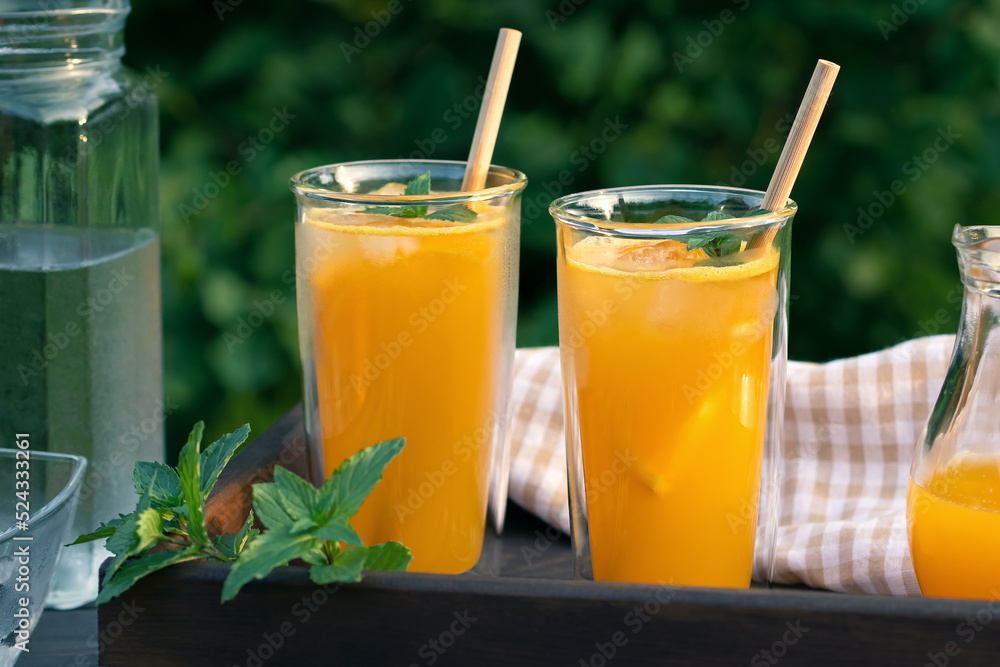 Fototapeta premium Refreshing summer homemade orange cocktail in tall double glass glasses with mint and ice, selective focus