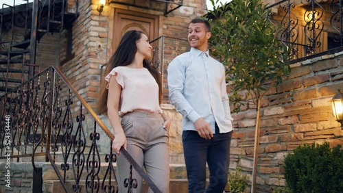 A young couple talking while moving down the stairs leaving their house and going to dinner.