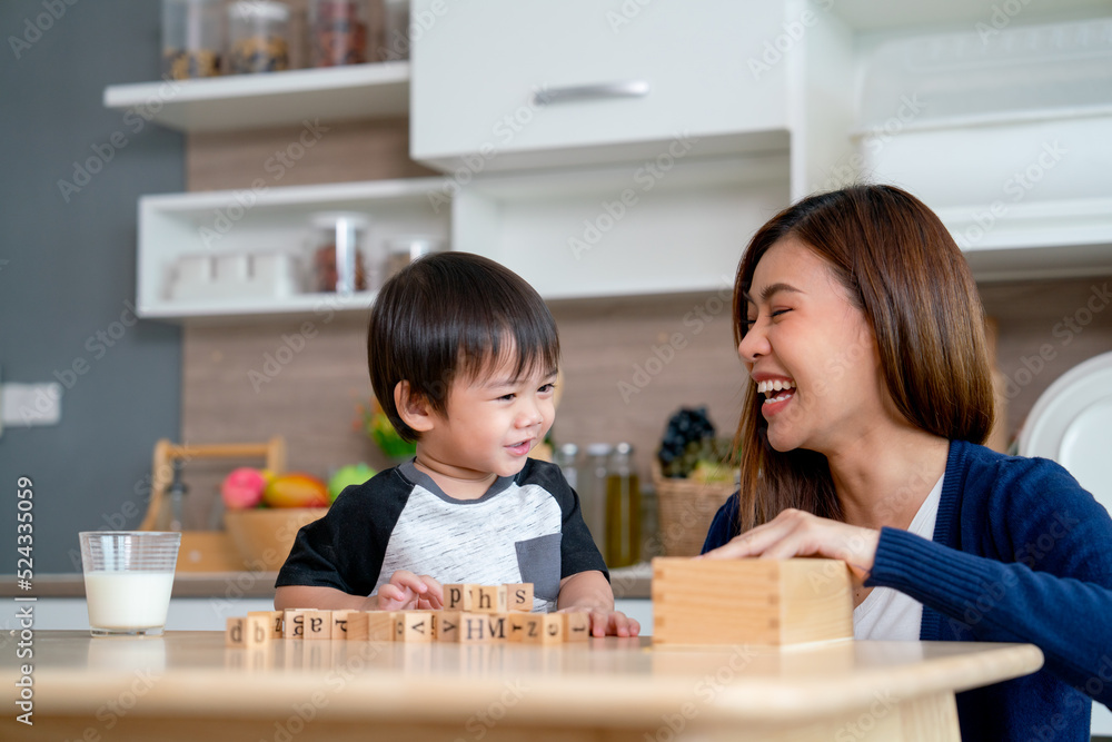 Asian mother enjoy to play wooden jigsaw puzzle together in area of kitchen of their house and they look happiness. Asian mother enjoy to play wooden jigsaw puzzle together in area of kitchen of their house and they look happiness.