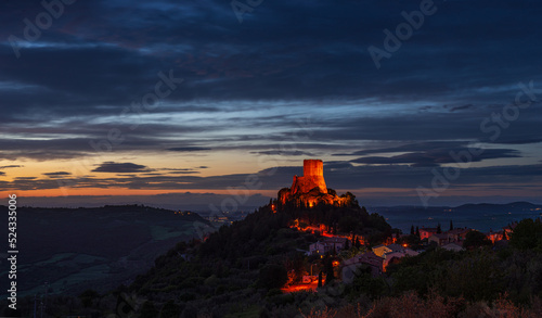 Rocca d'Orcia, a medieval village and fortress in Tuscany, Italy. Unique view at dusk, the stone tower perched on rock cliff against dramatic sky.