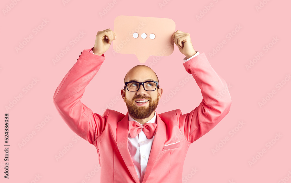 Smiling young man in suit on pink studio background hold speech bubble with  dots. Happy funny male in jacket show balloon or banner for online  communication. Messenger app concept. Stock Photo |