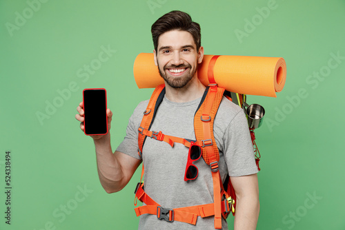 Young fun traveler white man carry backpack stuff mat use blank screen mobile phone isolated on plain green background Tourist lead active lifestyle walk on spare time Hiking trek travel trip concept #524338494