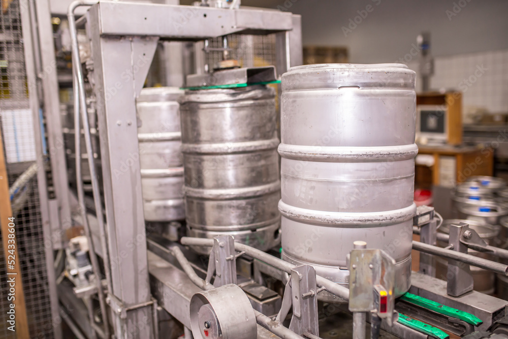 Brewery, bottling beer on aluminum kegs on conveyor lines. Industrial work, automated modern food and beverage production.