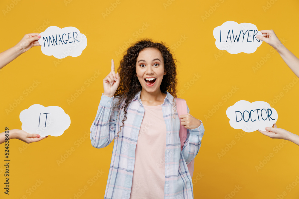 Young happy fun black teen girl student she wear casual clothes backpack bag point index finger up choose profession isolated on plain yellow color background. High school university college concept. Young happy fun black teen girl student she wear casual clothes backpack bag point index finger up choose profession isolated on plain yellow color background. High school university college concept.