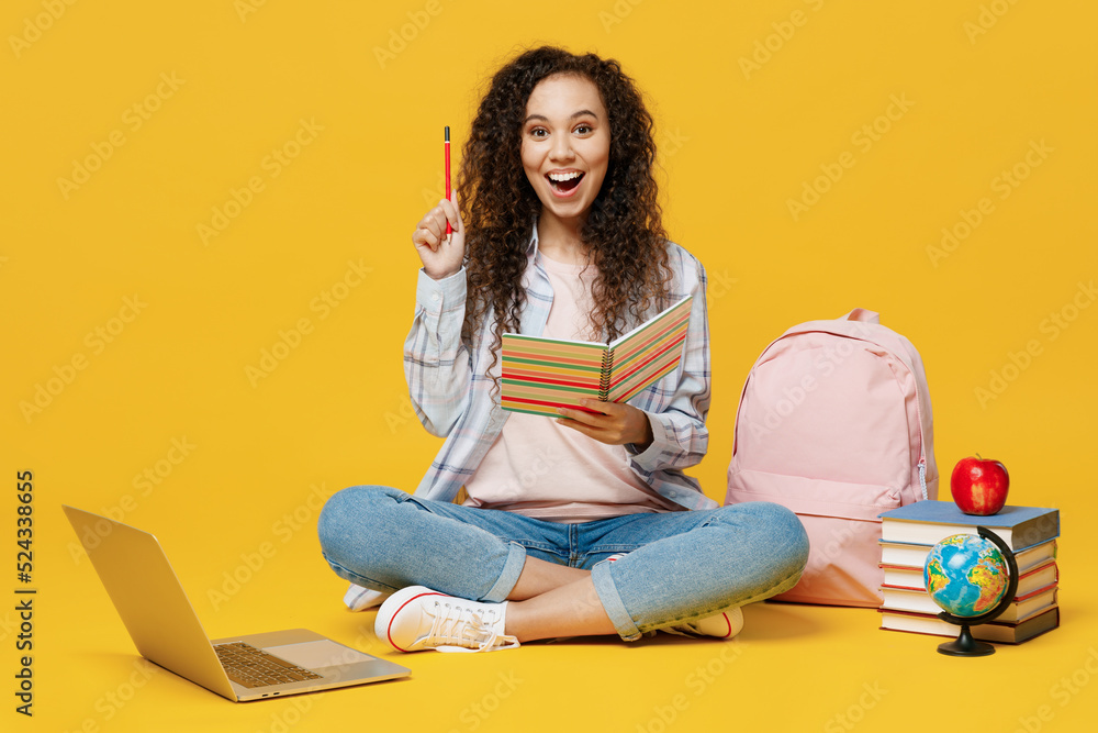 Full body smart young black teen girl student she wear casual clothes backpack bag sit read book point index finger up isolated on plain yellow color background High school university college concept Full body smart young black teen girl student she wear casual clothes backpack bag sit read book point index finger up isolated on plain yellow color background High school university college concept