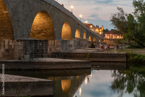 Steinerne  Brücke in  Regensburg am Abend, beleuchtet , Blick  auf den Dreifaltigkeitsberg im Hintergrund photo