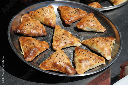 Traditional Uzbek patties (samsa) with chicken meat, lying on a large metal dish